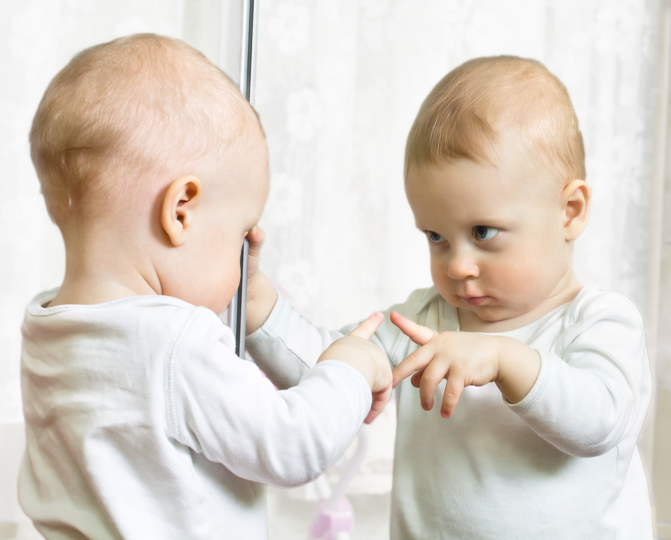 Ten month boy stands before the mirror