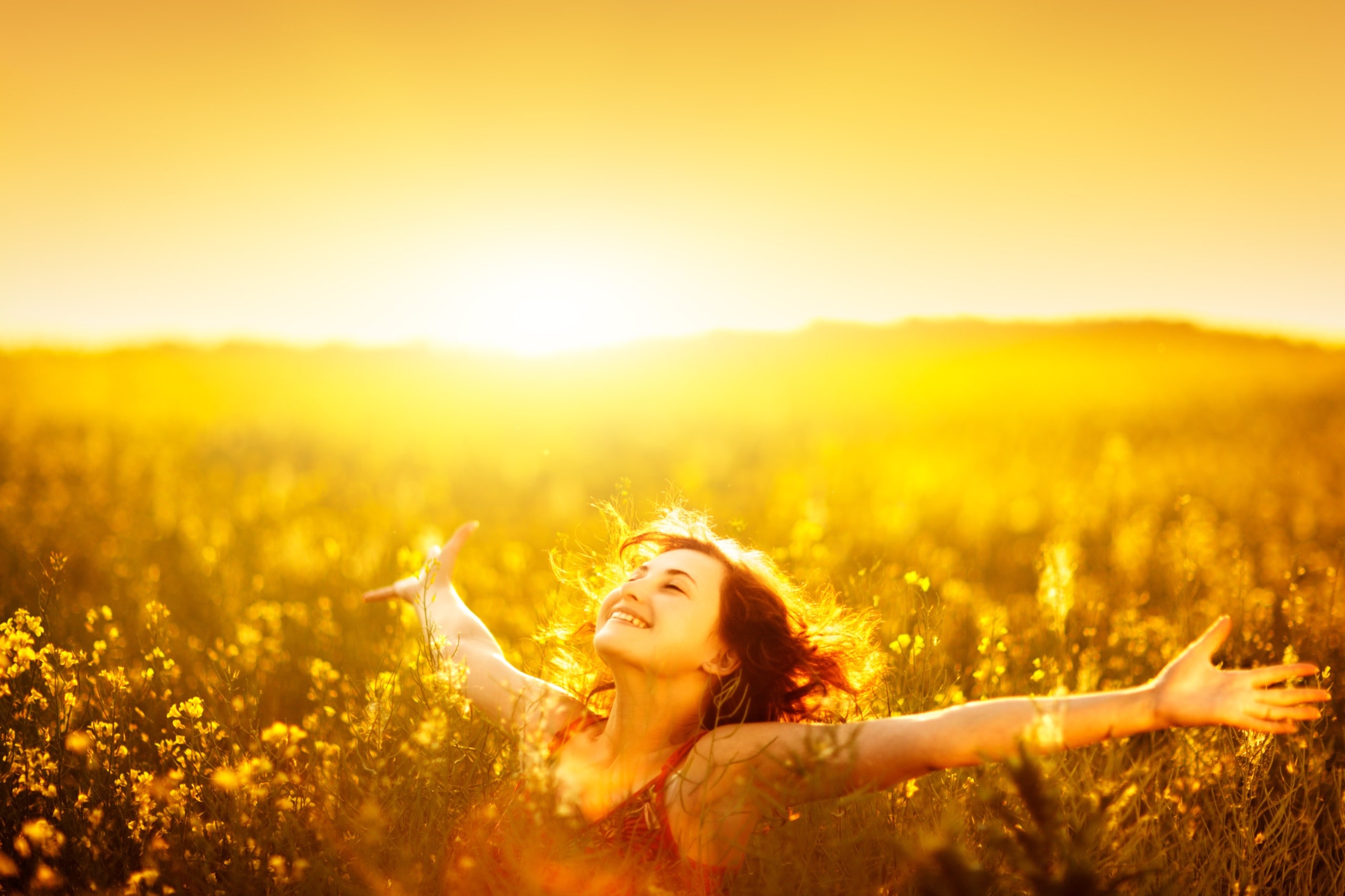 Young happy woman in canola field on sunset.