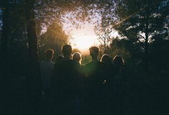 a group of friends watching sunrise in the forest